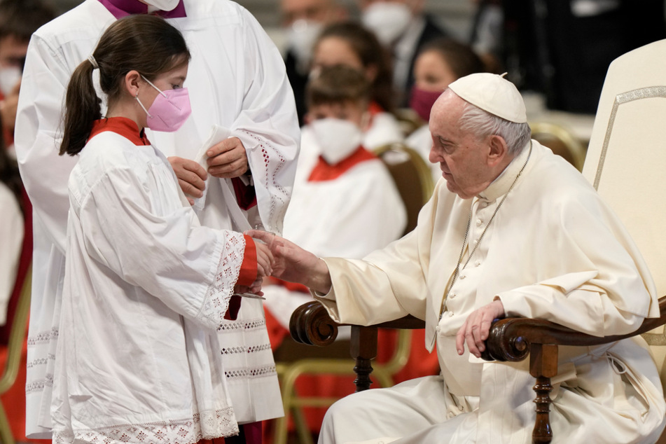 Ein Mädchen bietet Papst Franziskus ein Glas Wasser an, während er der Messe für die Göttliche Barmherzigkeit im Petersdom vorsteht.
