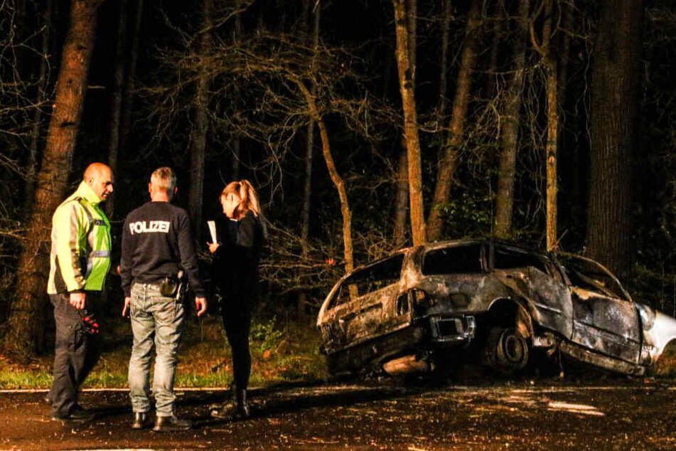 Die Polizei steht neben dem Wrack.