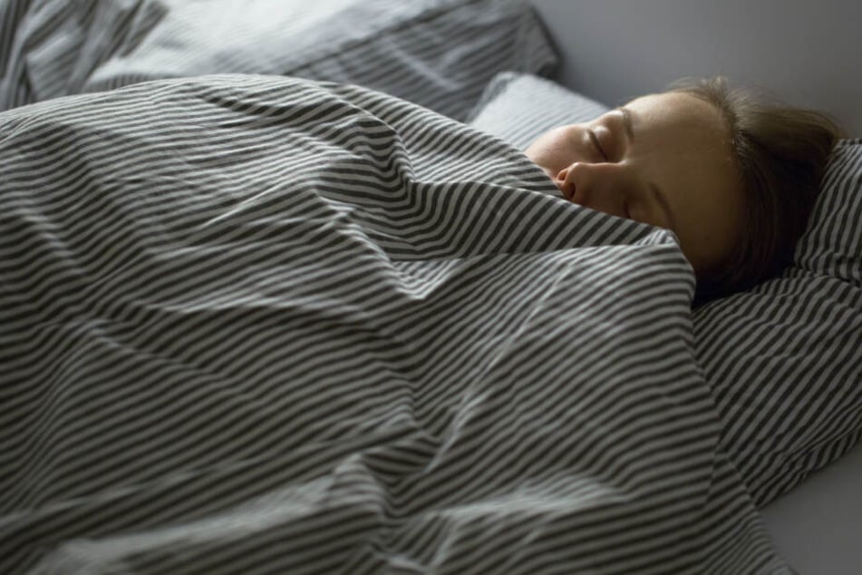 Eine Frau hat es sich in einem fremden Bett bequem gemacht. (Symbolbild)