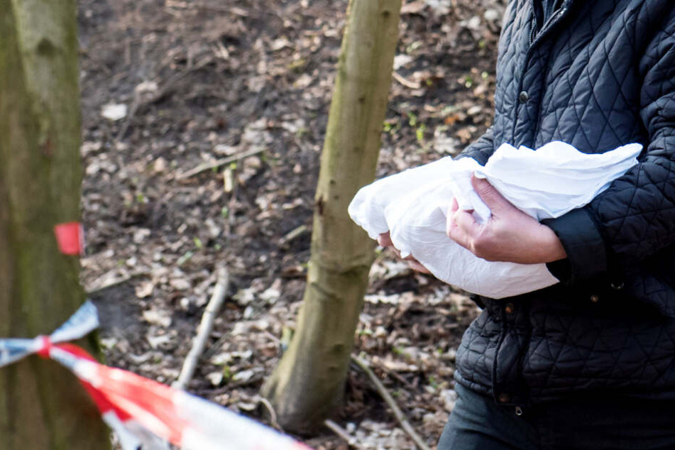 Ein Bestatter trägt das tote Baby vom Fundort weg.