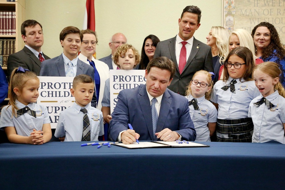 Florida governor Ron DeSantis signs the Parental Rights in Education, aka the Don't Say Gay bill, flanked by elementary school students during a news conference on March 2022.