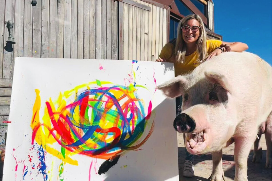 Pigcasso and his owner Joanne Lefson pose next to one of the pig's artistic creations.