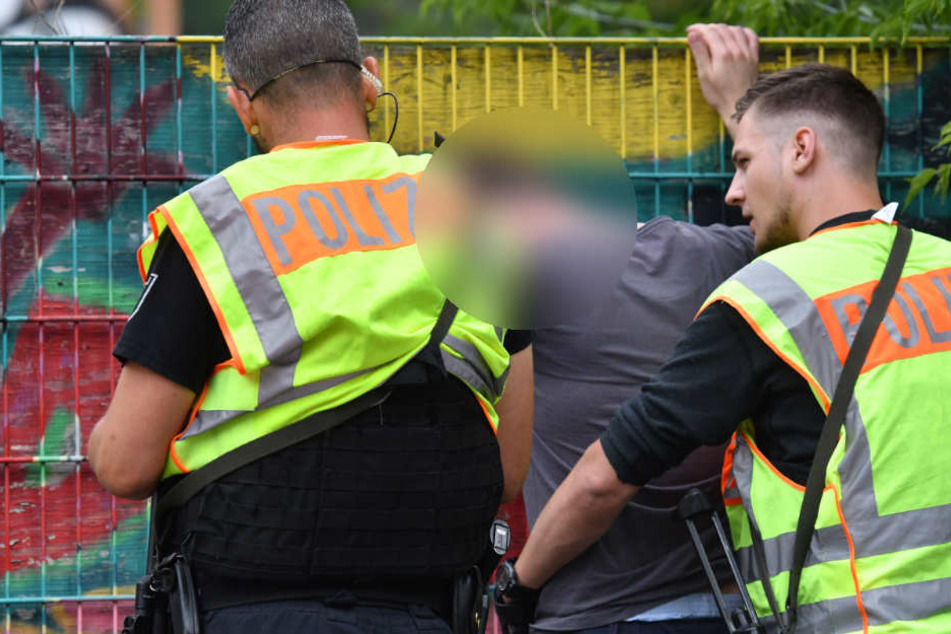 Polizisten durchsuchen eine Mann an einer Berliner Grundschule in Gesundbrunnen im Bezirk Mitte.