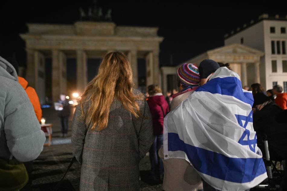 Teilnehmer stehen bei der Mahnwache von "Never Forget October 7th" vor dem Brandenburger Tor.