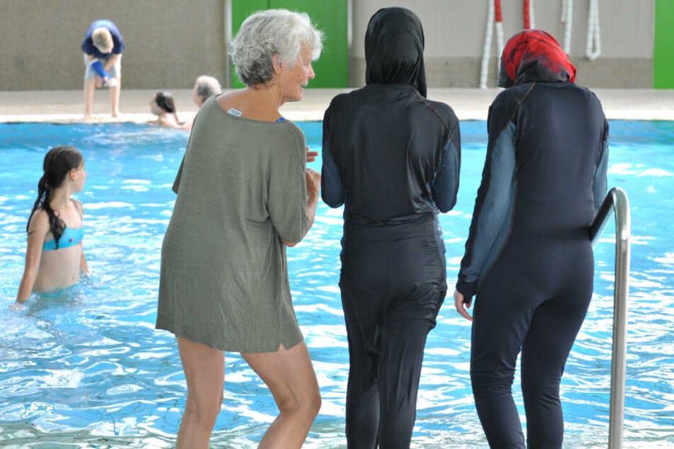 Zwei Schülerinnen stehen in ihren Burkinis vor dem Schwimmbecken.