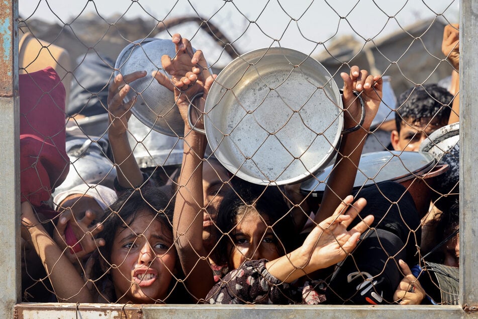 Palestinians, mostly children, wait to receive a hot meal at a charity kitchen in the Mawasi area of Khan Younis in the southern Gaza Strip on July 22, 2025.