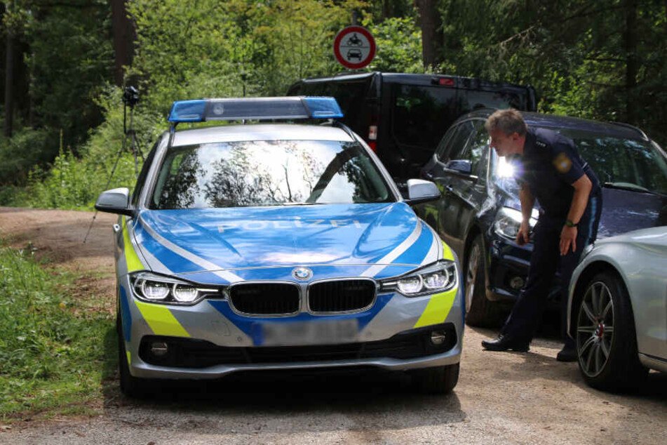 Die Polizei steht nach einem Leichenfund auf einem Waldweg. (Symbolbild)