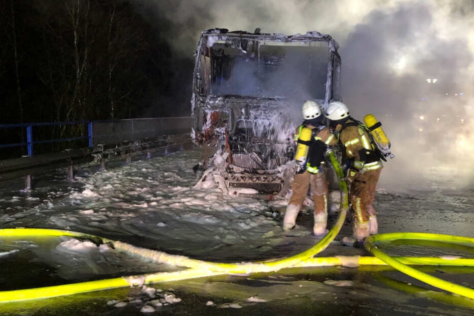 Feuerwehrleute löschen das brennende Führerhaus.