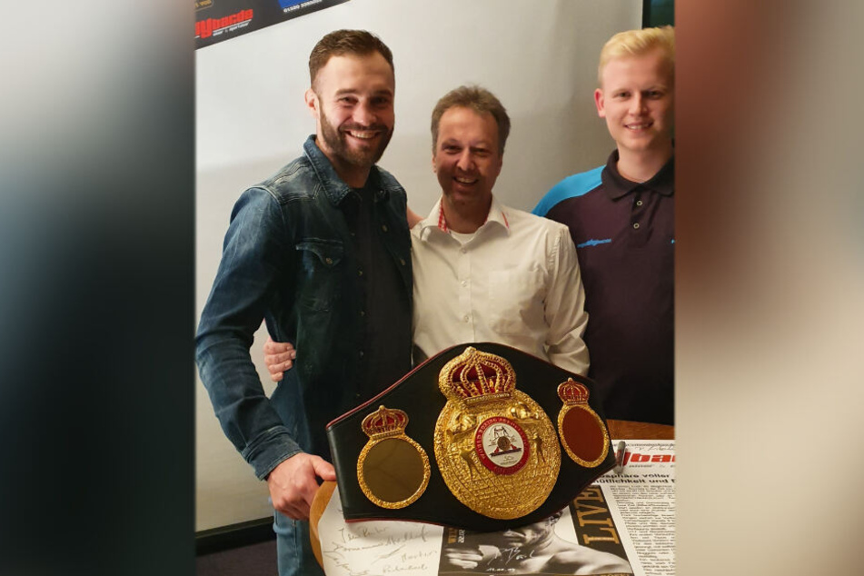 Foto mit Weltmeistergürtel (v.l.): Dominic Bösel (30), Sven Meyer (44) und Dart-Spieler Sven Hesse (19).