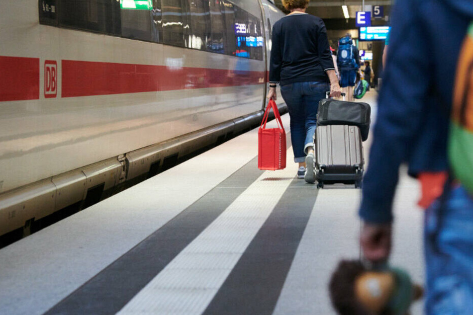 Reisende gehen neben einem ICE, der gerade im Hauptbahnhof eingetroffen ist.