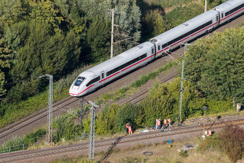 Mitarbeiter der Deutschen Bahn arbeiten nach dem Brand an einer Bahnstrecke in der Nähe eines Stellwerkes.