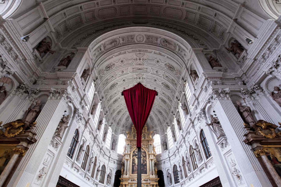 Ein rotes Tuch verhüllt in der St. Michael Kirche das Kreuz vor dem Altar. In vielen Kirchen werden Darstellungen von Jesus in der Zeit vor Ostern verhüllt, um sie an Karfreitag in einem Gottesdienst wieder feierlich zu enthüllen.