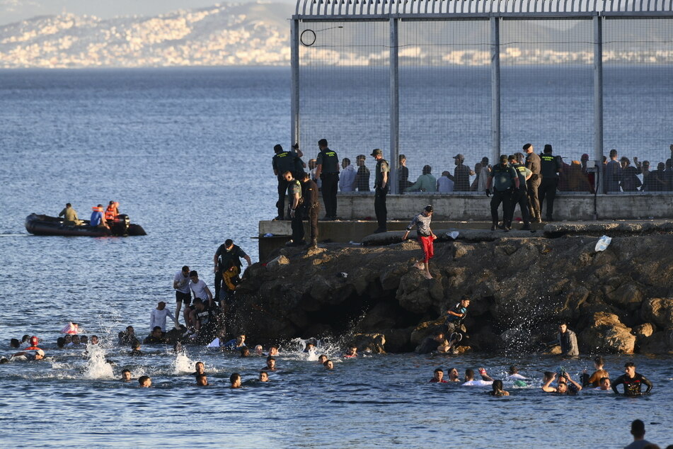 Spanische Beamte der Guardia Civil beobachten an der marokkanisch-spanischen Grenze in der spanischen Enklave Ceuta, wie Menschen aus Marokko schwimmend in spanisches Territorium eindringen.