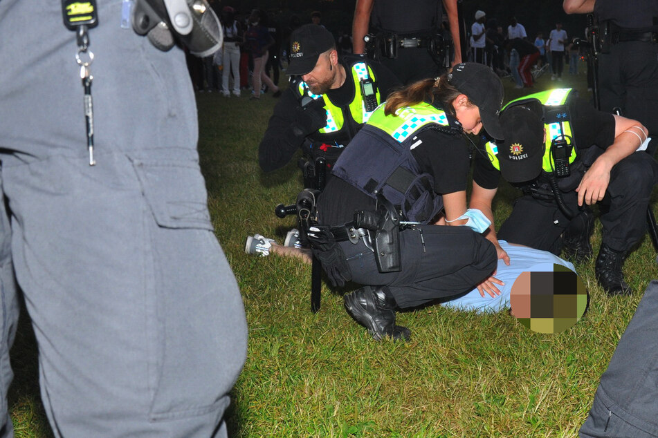 Polizeibeamte halten einen Mann im Stadtpark am Boden fest.