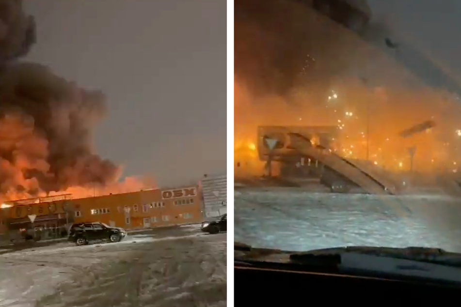 Ein Mann fährt auf den Parkplatz des brennenden Einkaufszentrums, dann wird es richtig gefährlich: Die Explosion reißt Gebäudeteile aus der Fassade.
