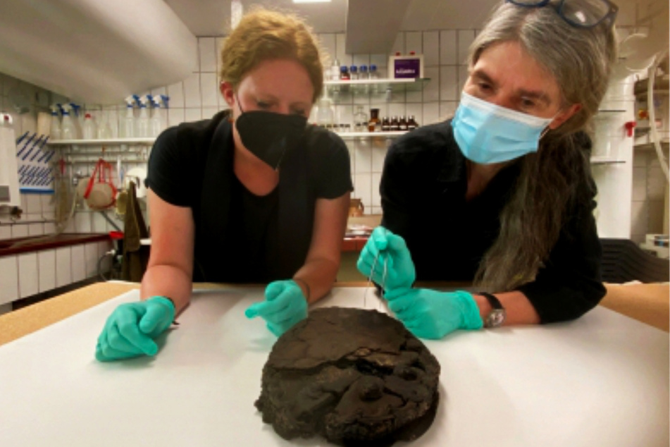 Lisa Renn (l.) und Doris Mührenberg inspizieren den beim Luftangriff 1942 verschütteten Fund: eine Nusstorte mit Krokant-Ummantelung.