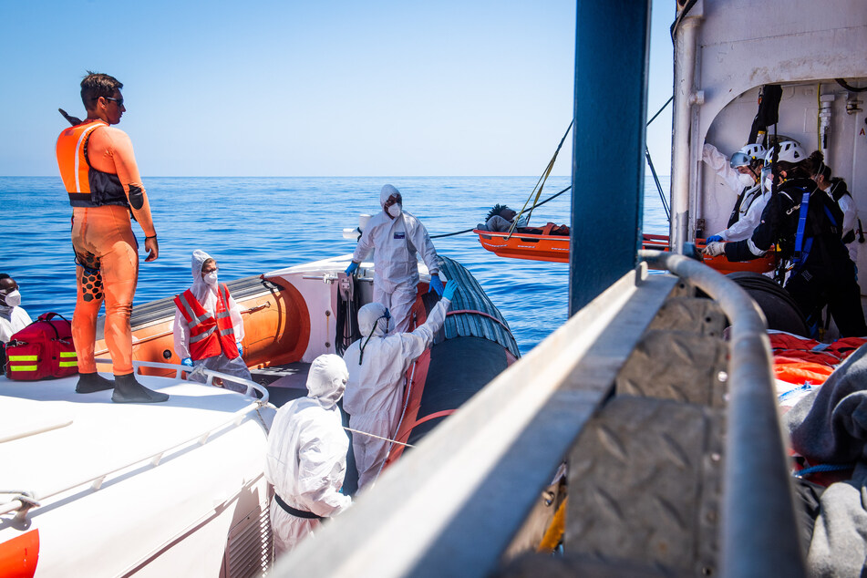 Helfer des Seenotrettungsschiffs "Sea-Watch 4" übergeben einen jugendlichen Flüchtling mit Treibstoff-Verbrennungen an die italienische Küstenwache.
