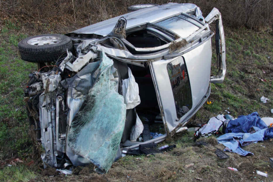 Das Wrack des Autos liegt neben der Fahrbahn in einem Grünstreifen.