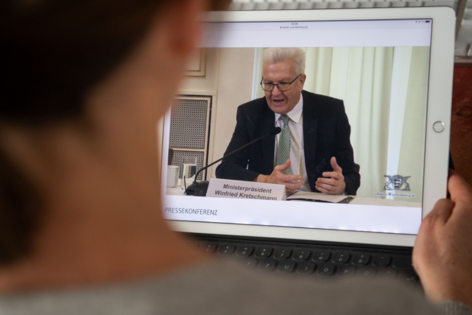 Eine Frau verfolgt auf einem Tablet eine Pressekonferenz, an der Winfried Kretschmann, Ministerpräsident von Baden-Württemberg, teilnimmt. Die Pressekonferenz der Landesregierung fand angesichts der Lage nur per Livestream statt.