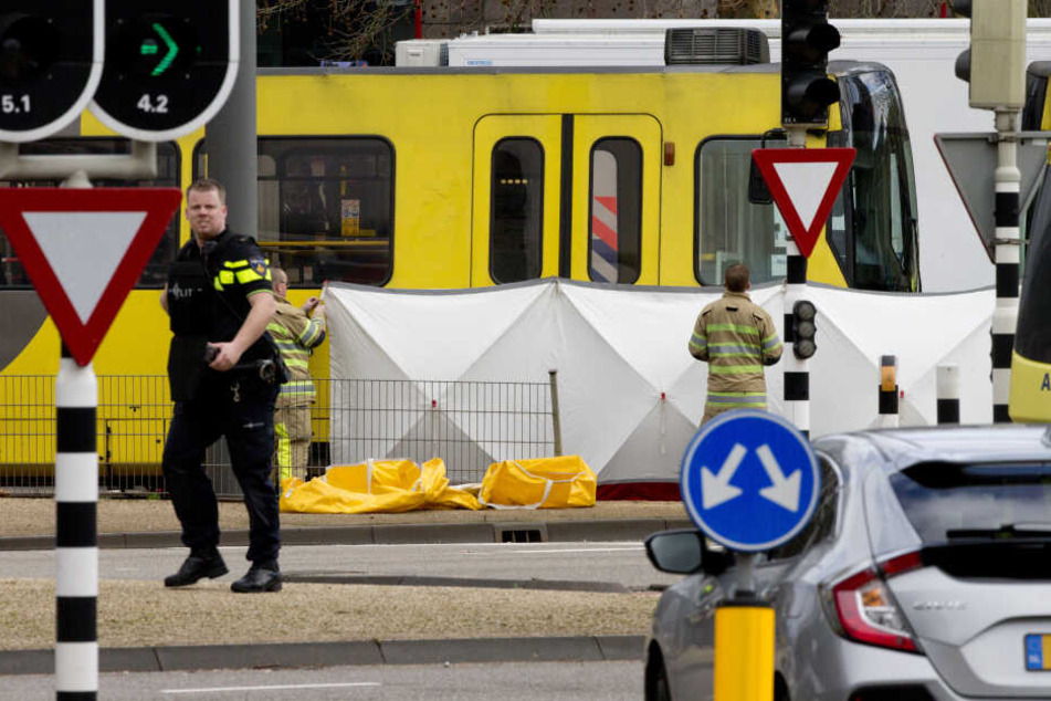 Ein Polizist steht an einem Sichtschutz vor einem Straßenbahnwagen.