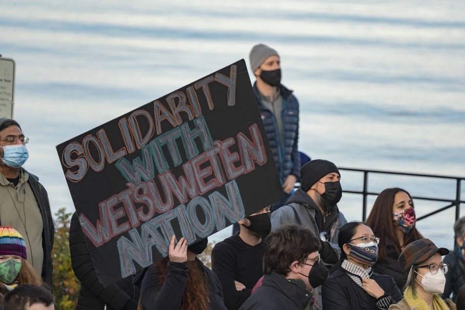 A demonstrator holds a sign reading "SOLIDARITY WITH WET'SUWET'EN NATION" during a rally to commemorate the National Day of Mourning at Plymouth Rock, Massachusetts.