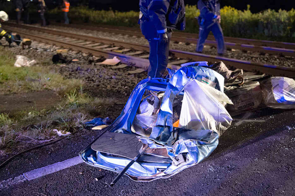 Polizeibeamte und Feuerwehrleute suchen Trümmerteile zusammen.