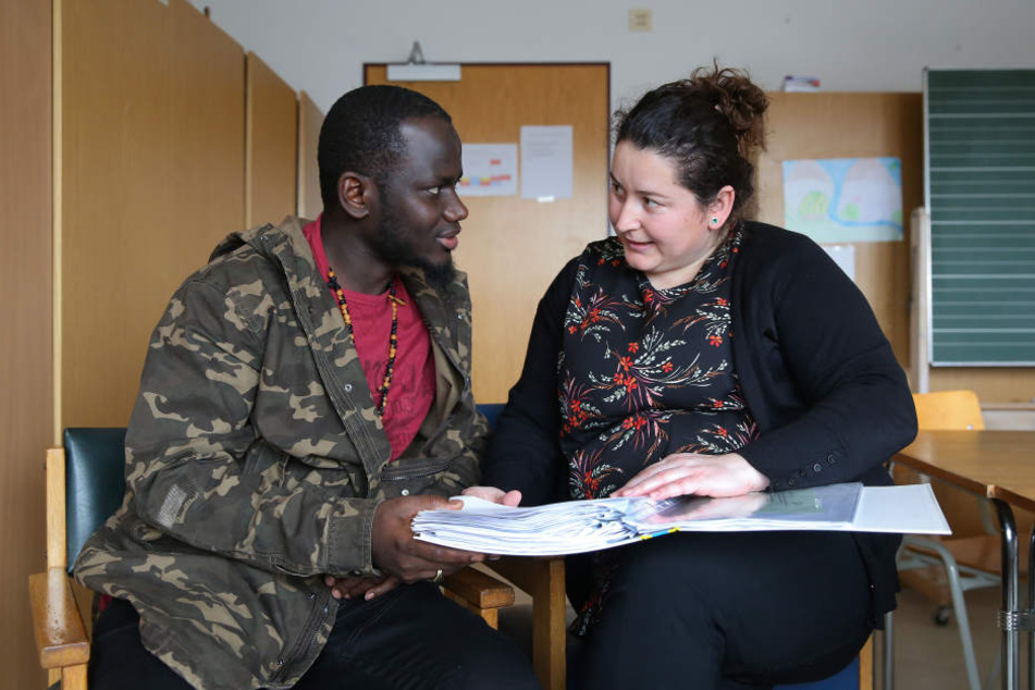Der Flüchtling Pa Saido Ngum (l.) aus Gambia unterhält sich in einer Flüchtlingsunterkunft mit der Sozialarbeiterin Najla Dervina (r.).