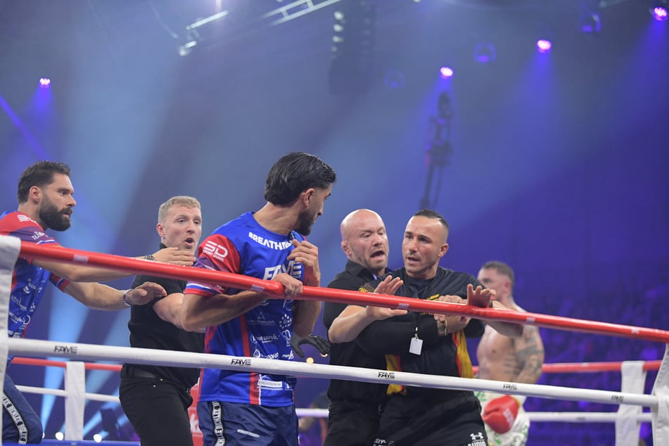 Gegnerische Mitglieder der Trainerteams gehen sich im Ring an.