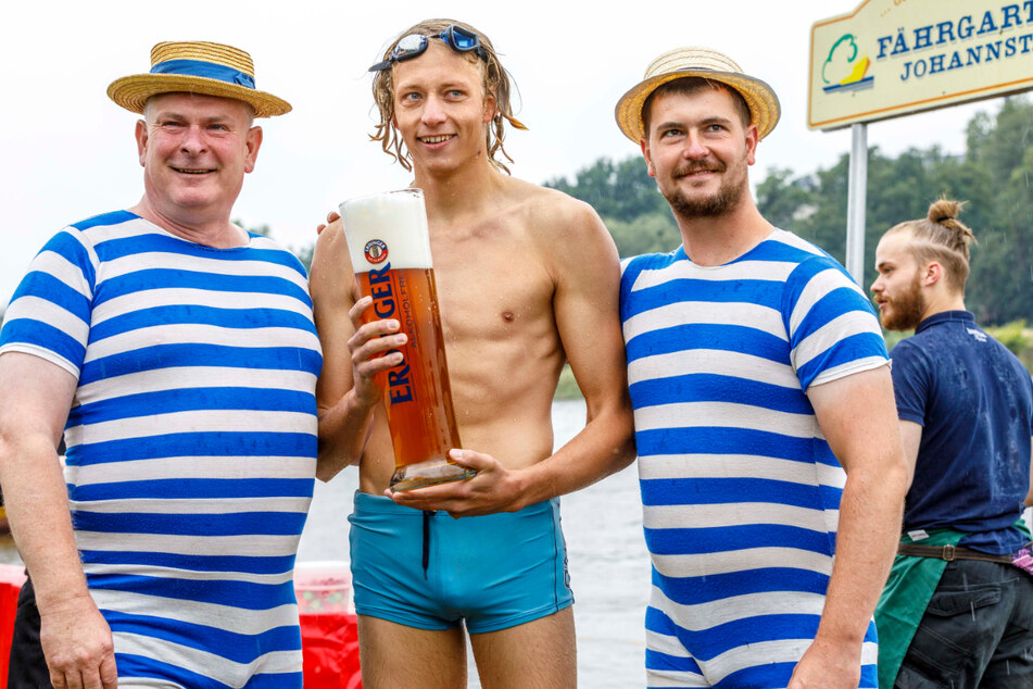 "Fährgarten"-Wirt Jens Bauermeister (56, l.) überreicht dem Sieger Martin Liegert (26, Mitte) ein großes Pils.