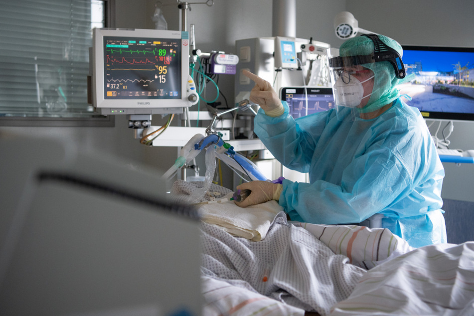 Eine Intensivpflegerin versorgt einen schwer an Corona erkrankten Patienten auf der Intensivstation eines Klinikums.