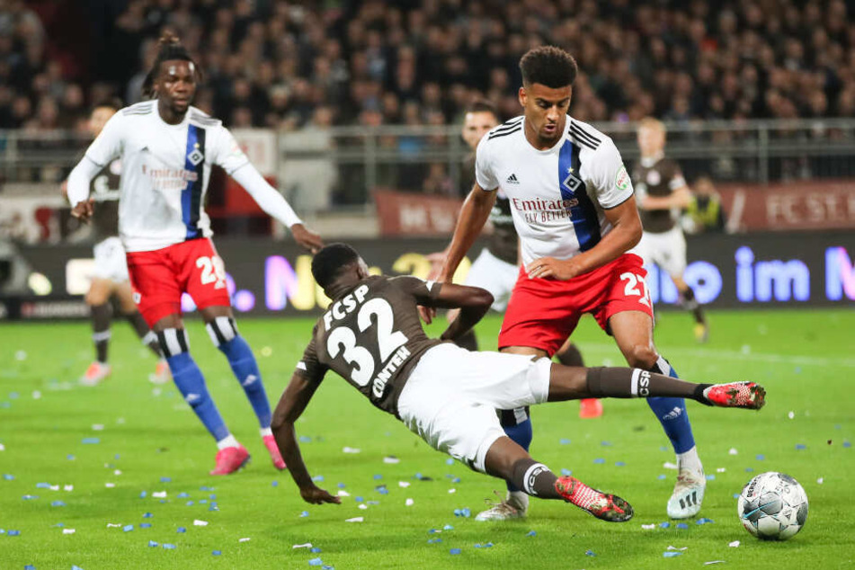 St. Paulis Christian Conteh fliegt in seinem Zweikampf mit HSV-Spieler Josha Vagnoman zu Boden.