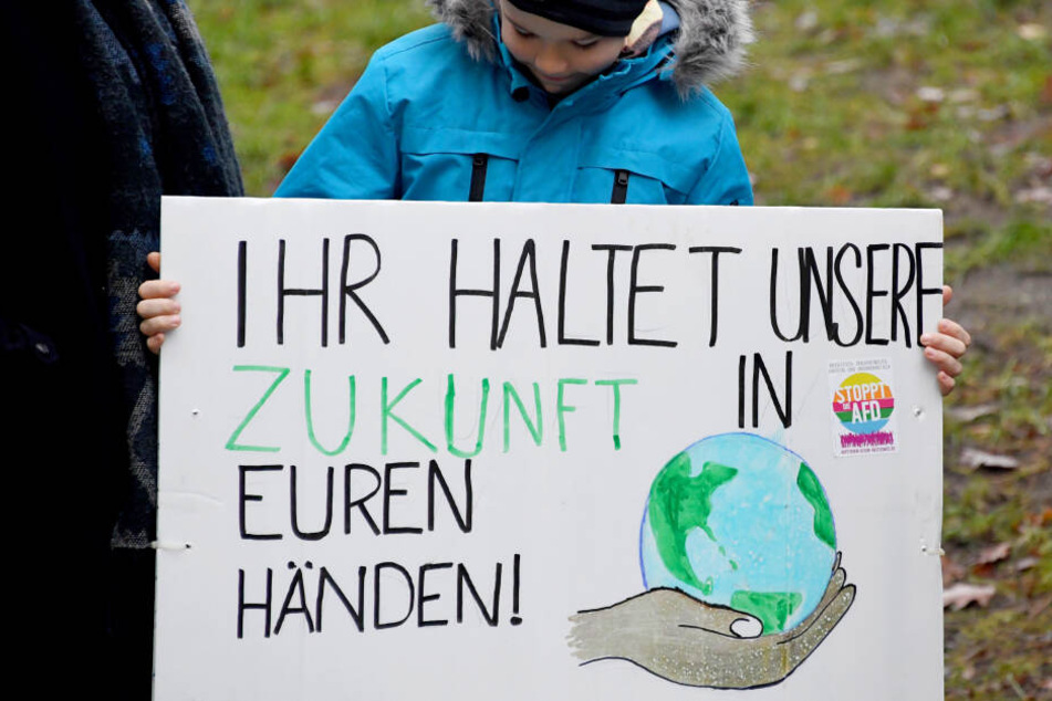 Schleswig-Holstein, Kiel: Mit einem Schild mit der Aufschrift "Ihr haltet unsere Zukunft in den Händen" steht ein Schüler bei einem Demonstrationszug.