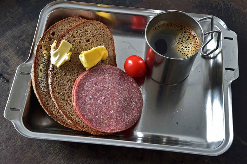 Caro-Kaffee, Brot, Margarine, Wurst und eine Tomate, serviert mit Plastebesteck, so sieht Essen im Knast aus.