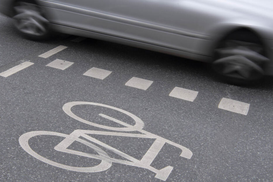 Ein Auto fährt an einer Kreuzung an einem Radweg vorbei.