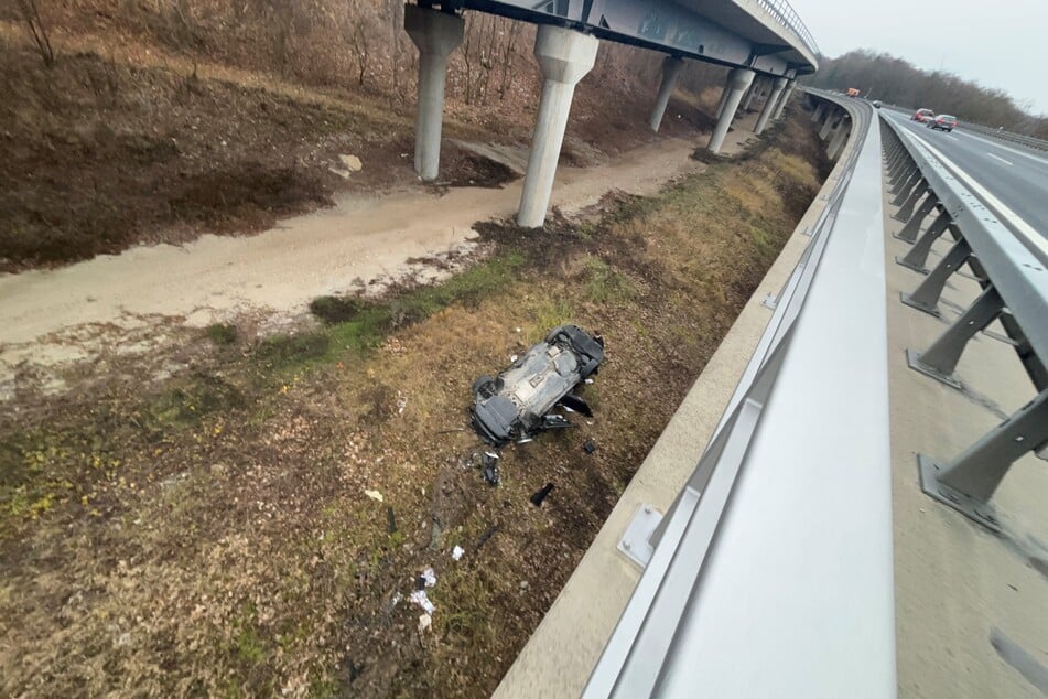 Ein Auto liegt auf dem Dach unterhalb einer Autobahnbrücke bei Scheßlitz im Landkreis Bamberg.