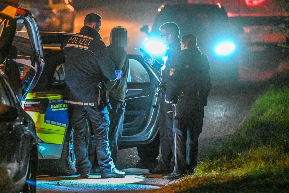 Beamte der Schutzpolizei führen in der Nacht einen mutmaßlichen Tatverdächtigen ab.