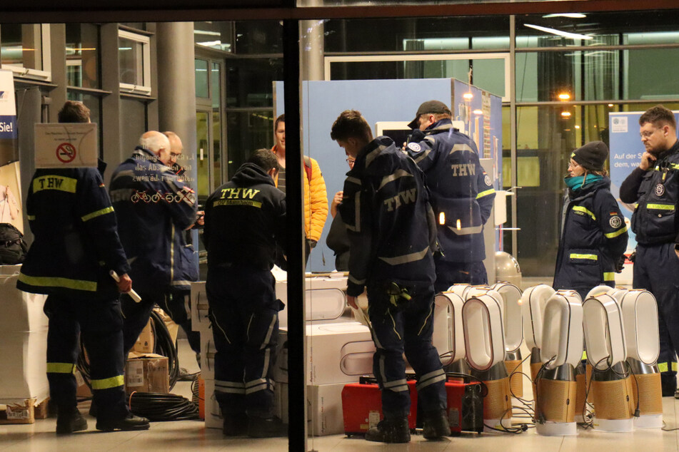 Helfer des Technischen Hilfswerks (THW) haben sich mit Raumklimageräten und weiterer Ausrüstung vor dem Uniklinikum Heidelberg eingefunden.