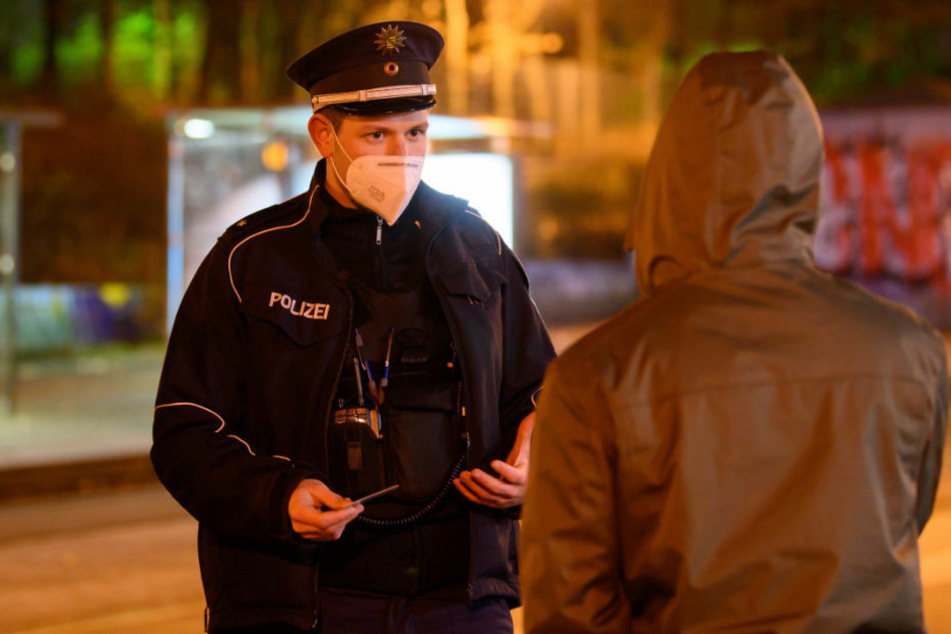 Ein Polizist kontrolliert die Einhaltung der Corona-Ausgangssperre. Der Landkreis Vorpommern-Greifswald hat die geltende Ausgangssperre nach einem Urteil des Verwaltungsgerichts wieder außer Kraft gesetzt. (Symbolfoto)