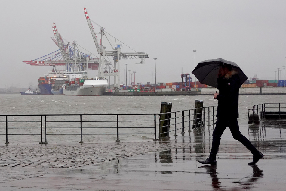 Ein Spaziergänger geht im Regen an der Elbe entlang. Die Menschen im Norden erwartet in den kommenden Tagen stürmisches Wetter.