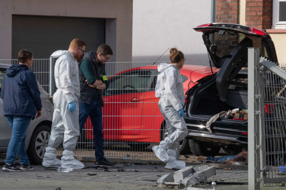 Mitarbeiter der Spurensicherung stehen an dem Wrack eines dunklen PKW, unter dem die Leiche einer Frau liegt (Archivbild).