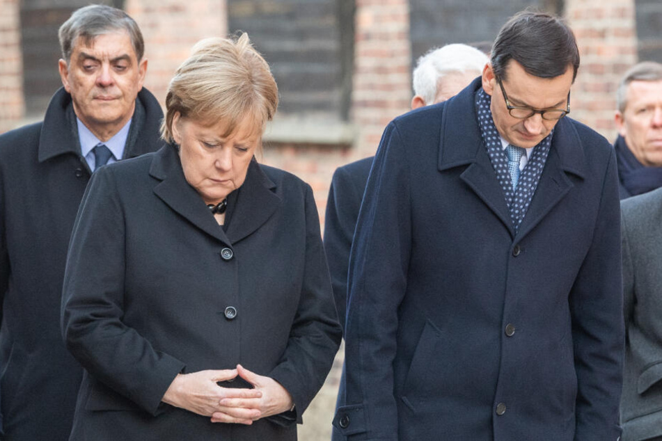 Bundeskanzlerin Angela Merkel (CDU) und Mateusz Morawiecki, Ministerpräsident von Polen, verneigen sich nach einer Kranzniederlegung an der Todesmauer im ehemaligen deutschen Konzentrationslager Auschwitz.