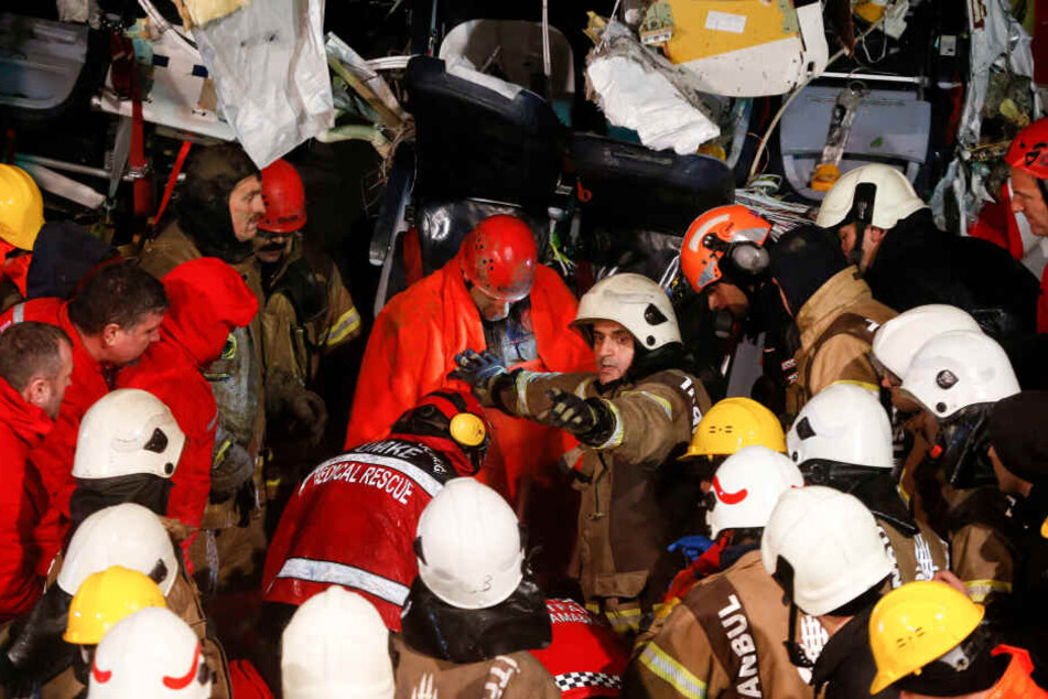Rettungskräfte evakuieren eine verletzte Person (M) aus dem Wrack des Flugzeugs.