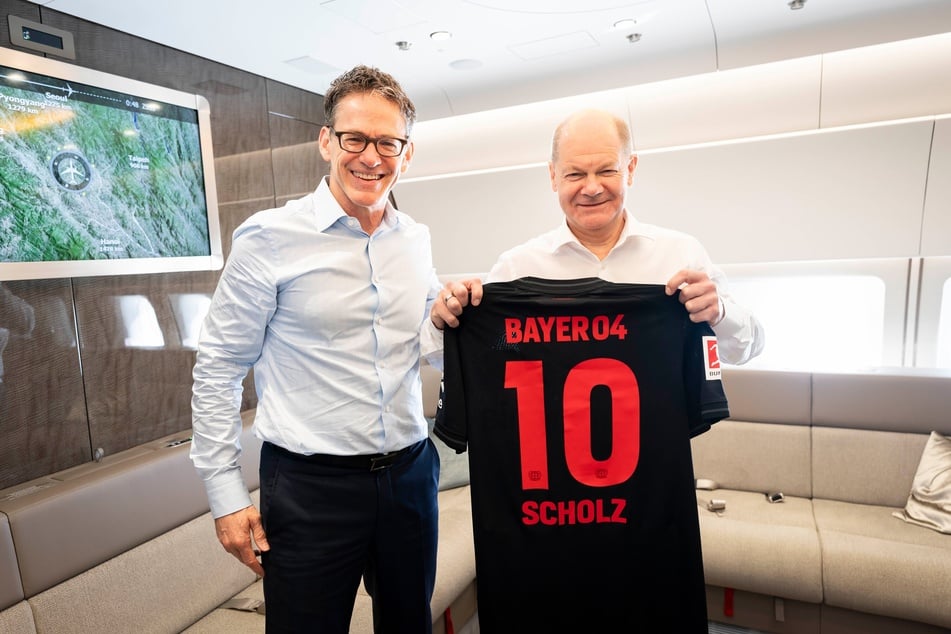 Das Rot nicht nur in den Parteifarben: Bundeskanzler Scholz (65) bekam von Bayer CEO Bill Anderson (57) die passende Meistergarderobe aus Leverkusen.
