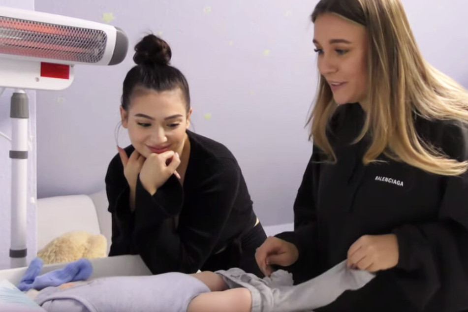 Paola Maria (25) zeigt ihrer Freundin Dagi Bee (24) wie man ein Baby wickelt.