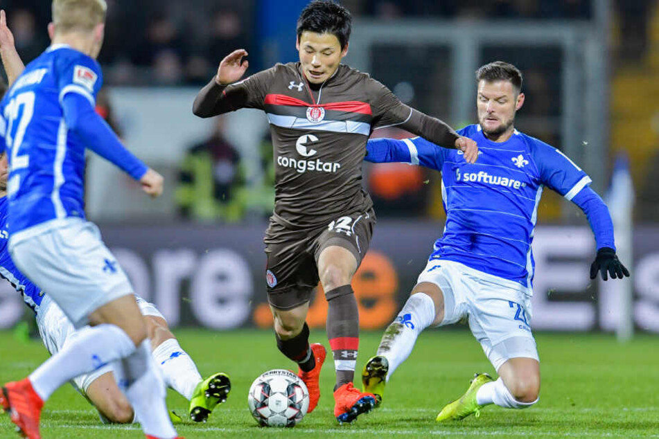 Ryo Miyaichi sieht sich gleich mehrerer grätschender Gegenspieler ausgesetzt.