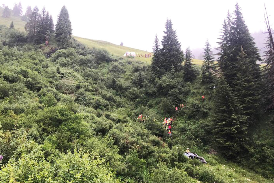 Rettungskräfte positionierten sich auf dem steilen Abhang und liefen zu dem Unglückswagen.