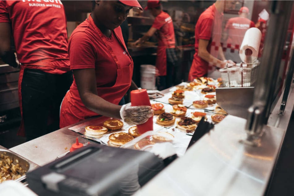 Five Guys Mitarbeiter bereiten Burger zu.