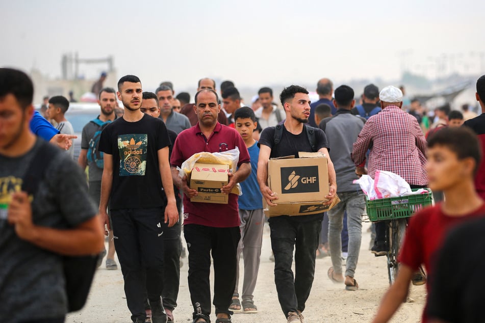 Palestinians carry boxes of relief supplies from the Gaza Humanitarian Foundation as they return from an aid distribution center in the central Gaza Strip on June 8, 2025.
