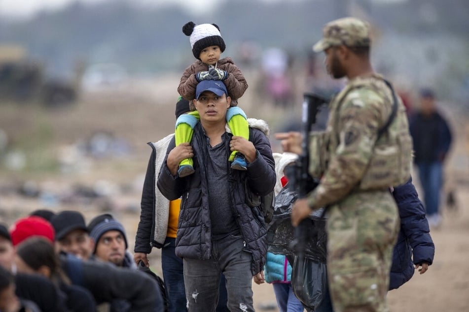 An armed Texas National Guard soldier counts a group of people who had crossed the US-Mexico border on December 20, 2023, in Eagle Pass, Texas.