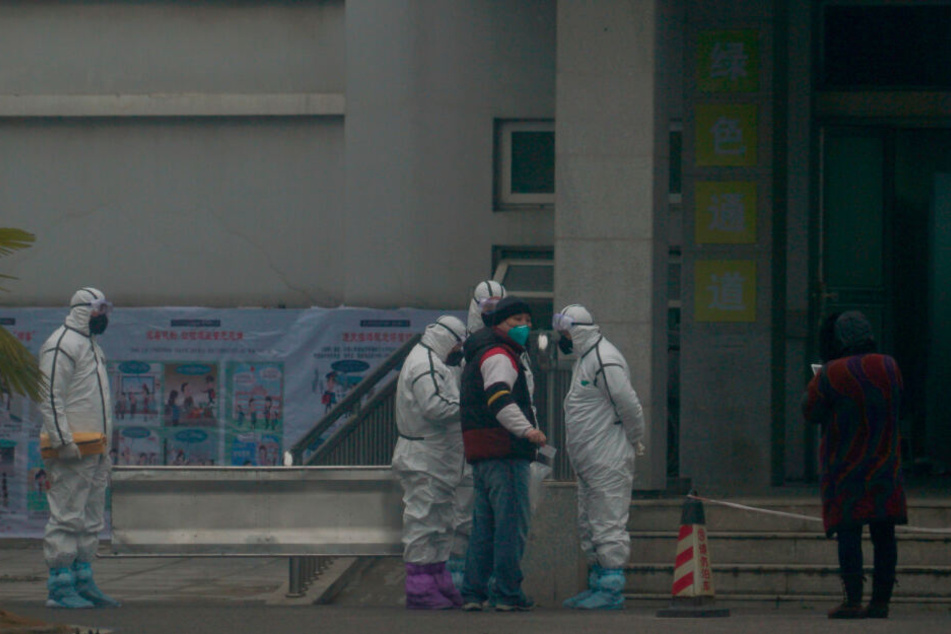 Mitarbeiter in Schutzanzügen stehen vor dem Wuhan Medical Treatment Center, in dem ein Patient mit Verdacht auf den neuartigen Corona-Virus behandelt wurde.